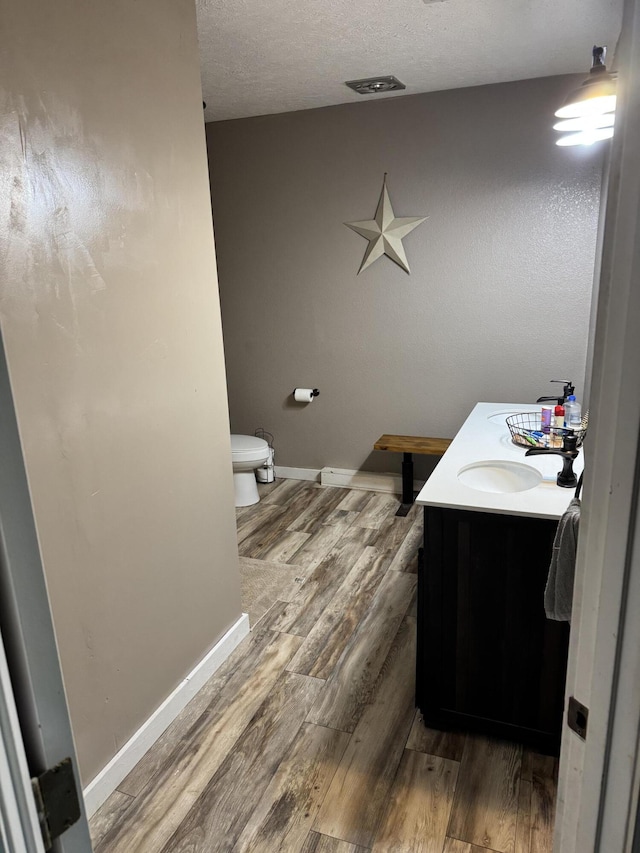 9153 N Hwy Highway, Mountain Grove, MO 65711 - bathroom featuring toilet, vanity, wood finished floors, baseboards, and a textured ceiling