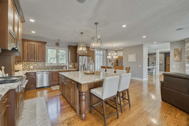 1865 N Hearthstone Ln, Strafford, MO 65757 - kitchen with stainless steel appliances, a breakfast bar area, recessed lighting, brown cabinets, and light wood finished floors
