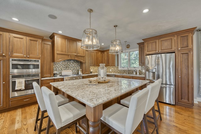 1865 N Hearthstone Ln, Strafford, MO 65757 - kitchen featuring stainless steel appliances, brown cabinetry, a center island, light wood finished floors, and recessed lighting