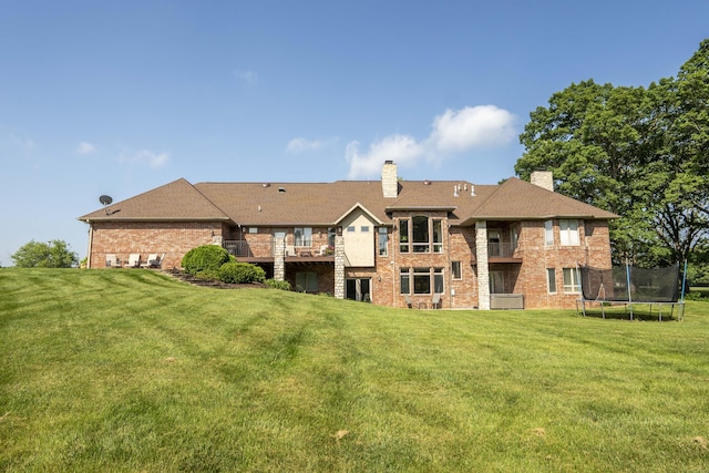 1865 N Hearthstone Ln, Strafford, MO 65757 - rear view of property featuring a trampoline, brick siding, a balcony, a chimney, and a yard