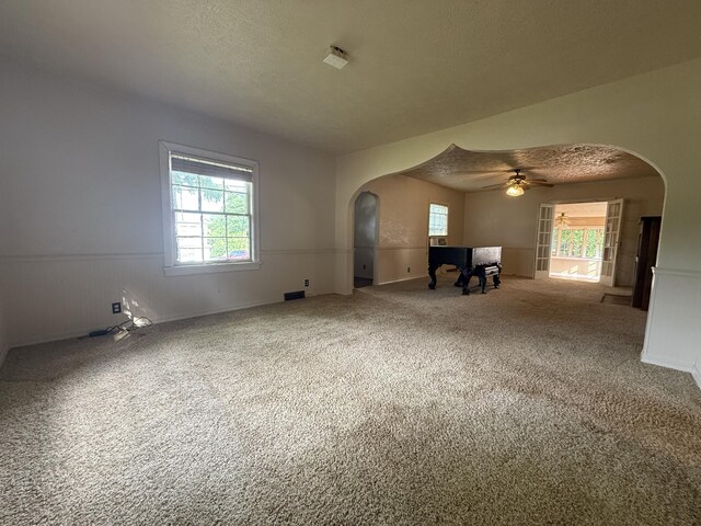 404 S 5th St, Thayer, MO 65791 - unfurnished living room with arched walkways, wainscoting, carpet, a ceiling fan, and a textured ceiling