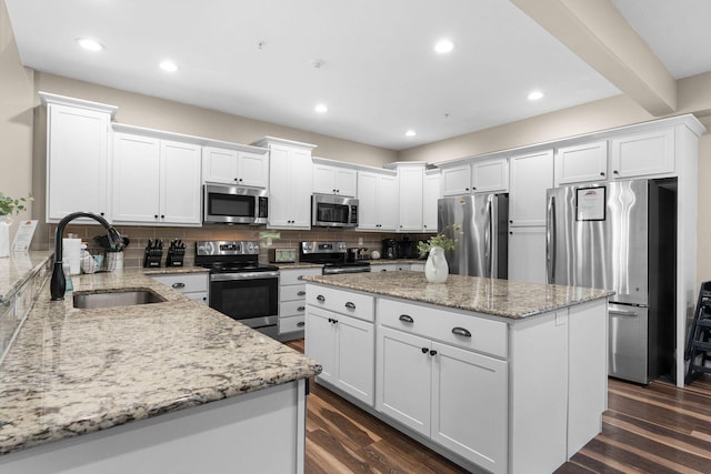 440 Lake Front Dr, Branson, MO 65616 - kitchen featuring stainless steel appliances, a sink, a kitchen island, decorative backsplash, and white cabinetry