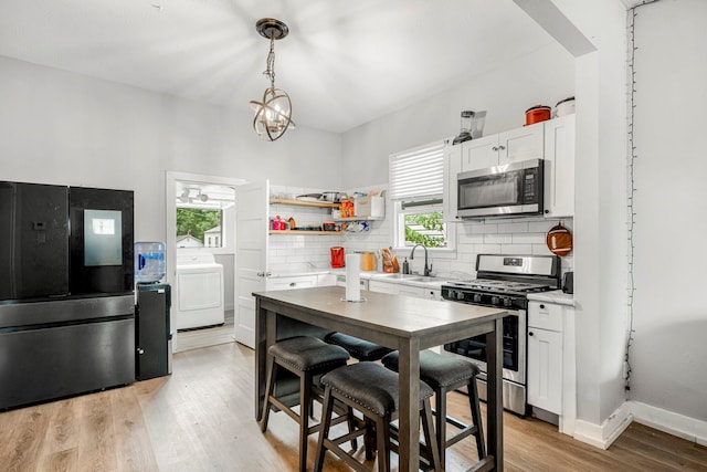 1609 N Lyon Ave, Springfield, MO 65803 - kitchen with stainless steel appliances, washer / clothes dryer, backsplash, light countertops, and plenty of natural light