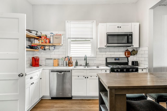 1609 N Lyon Ave, Springfield, MO 65803 - kitchen featuring stainless steel appliances, a sink, open shelves, and white cabinetry