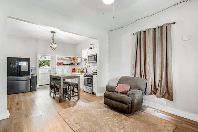 1609 N Lyon Ave, Springfield, MO 65803 - kitchen featuring stainless steel appliances, washer / clothes dryer, open shelves, white cabinets, and light wood-style flooring