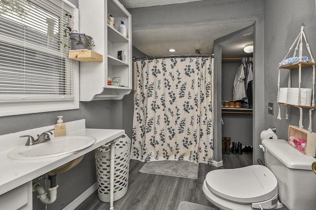 2052 N Grant Ave, Springfield, MO 65803 - bathroom with a textured ceiling, wood finished floors, curtained shower, toilet, and a sink