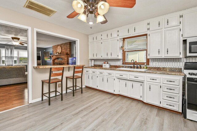 2052 N Grant Ave, Springfield, MO 65803 - kitchen with a sink, ceiling fan, white gas range oven, stainless steel microwave, and light wood-type flooring
