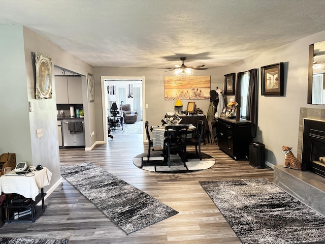 27641 County Road 356, Pittsburg, MO 65724 - dining room featuring wood finished floors, ceiling fan, a textured ceiling, a fireplace, and baseboards
