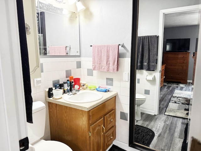 27641 County Road 356, Pittsburg, MO 65724 - bathroom featuring toilet, tile walls, wood finished floors, vanity, and a wainscoted wall