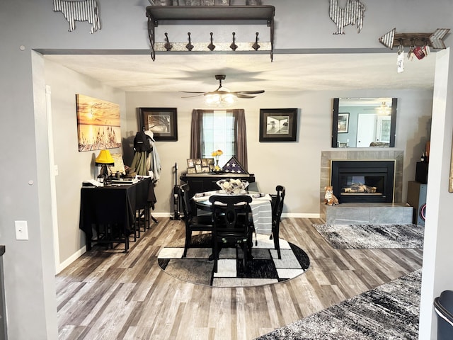 27641 County Road 356, Pittsburg, MO 65724 - dining space featuring wood finished floors, a ceiling fan, a glass covered fireplace, and baseboards