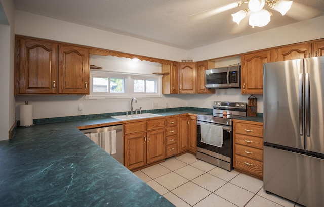 1603 W Northwood St, Bolivar, MO 65613 - kitchen with stainless steel appliances, brown cabinetry, a sink, dark countertops, and a ceiling fan