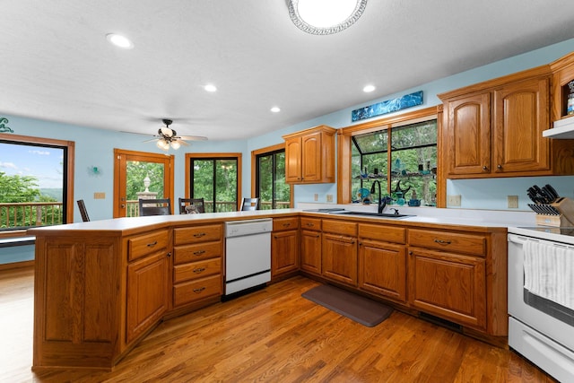 25158 Autumn View Dr, Shell Knob, MO 65747 - kitchen with white appliances, a peninsula, a sink, brown cabinetry, and light wood-style floors