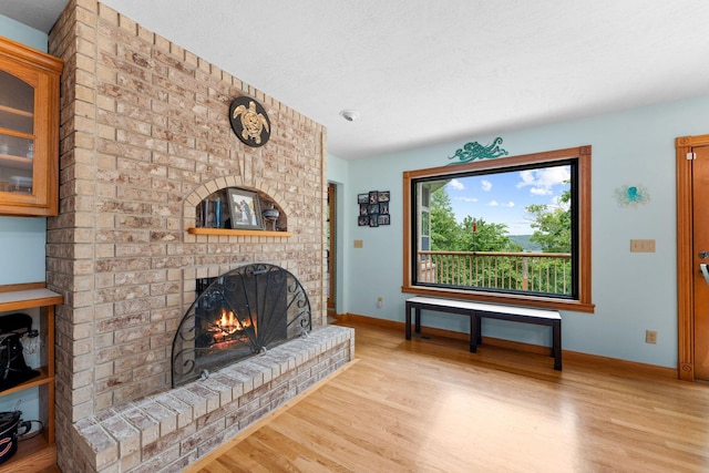 25158 Autumn View Dr, Shell Knob, MO 65747 - living area with wood finished floors, baseboards, a brick fireplace, and a textured ceiling
