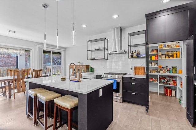 518 N Dublin Dr, Nixa, MO 65714 - kitchen with stainless steel gas stove, wall chimney exhaust hood, dark cabinets, light wood finished floors, and a sink