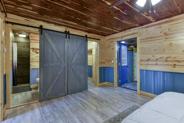 145 Allison Bnd, Lampe, MO 65681 - bedroom with wood walls, wood ceiling, a barn door, wood finished floors, and ensuite bath