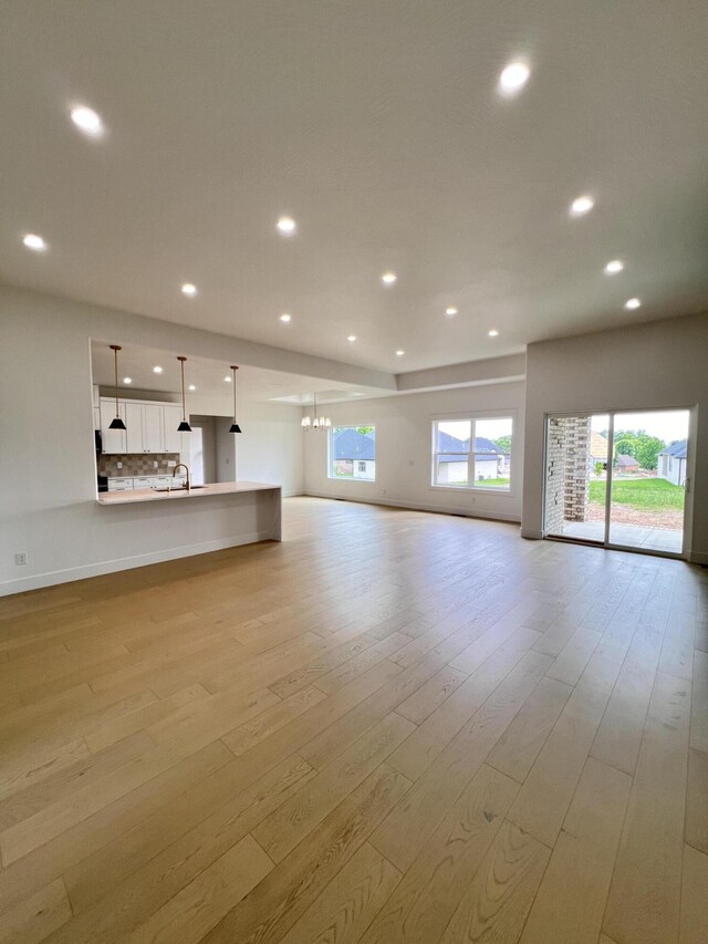 2090 N Silver Charm Ave, Springfield, MO 65802 - unfurnished living room with recessed lighting, a sink, plenty of natural light, and light wood-style flooring