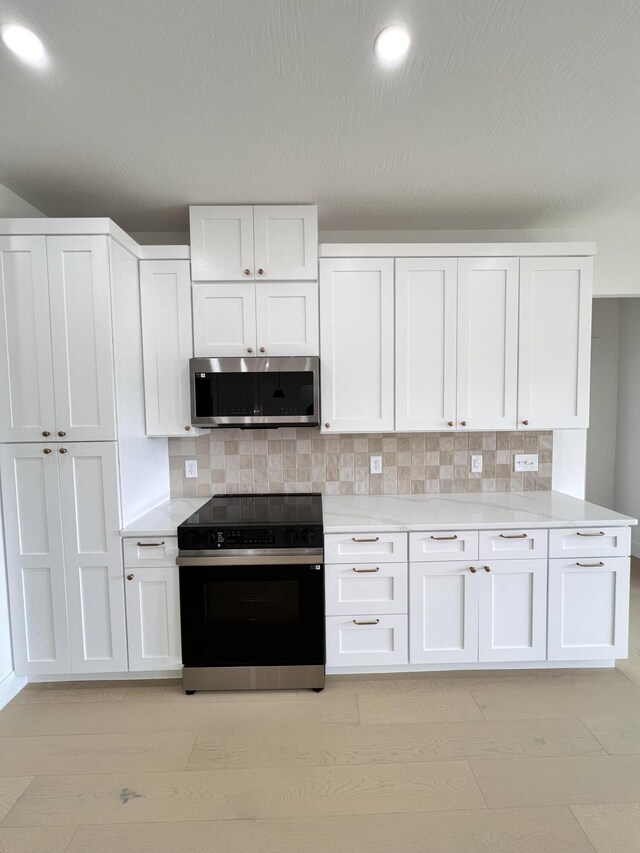 2090 N Silver Charm Ave, Springfield, MO 65802 - kitchen with stainless steel microwave, black / electric stove, white cabinetry, light countertops, and recessed lighting