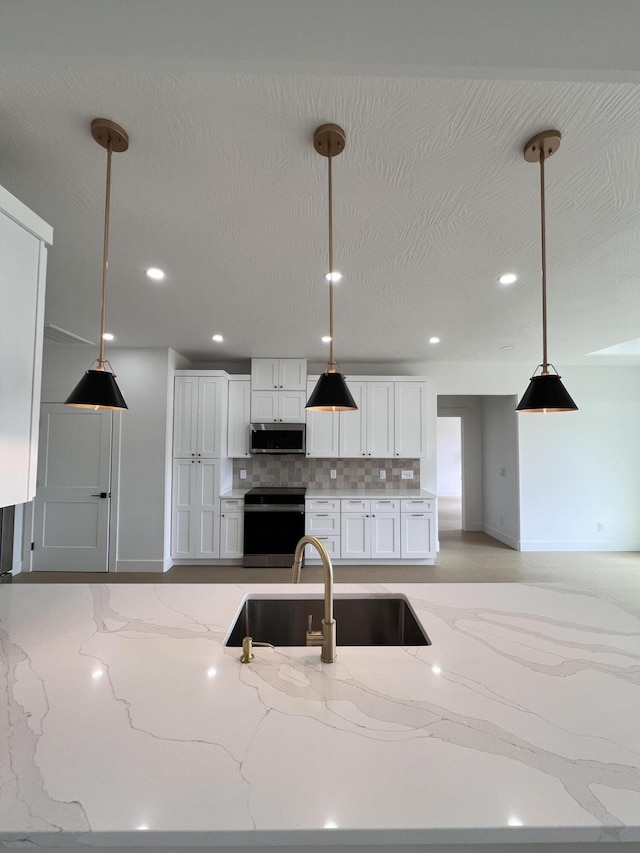 2090 N Silver Charm Ave, Springfield, MO 65802 - kitchen featuring stainless steel appliances, a sink, white cabinetry, tasteful backsplash, and hanging light fixtures