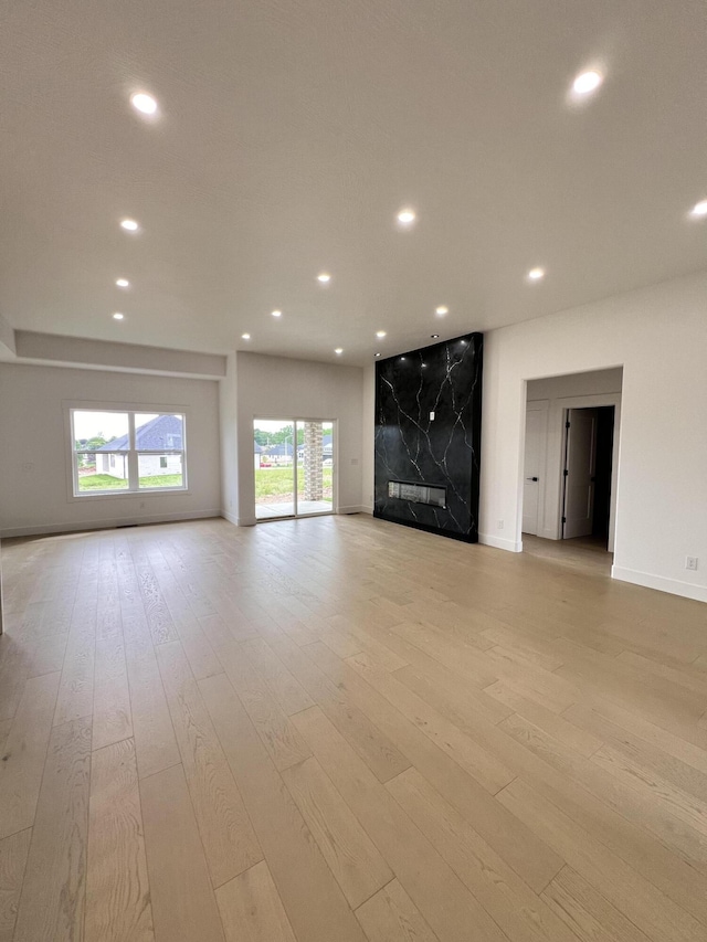 2090 N Silver Charm Ave, Springfield, MO 65802 - unfurnished living room featuring recessed lighting, light wood-style floors, baseboards, and a premium fireplace