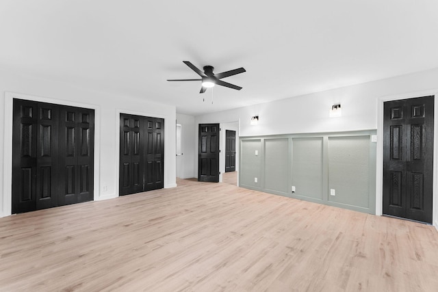 26237 Twin Rivers Dr, Shell Knob, MO 65747 - unfurnished bedroom with wood finished floors, two closets, a decorative wall, a ceiling fan, and wainscoting