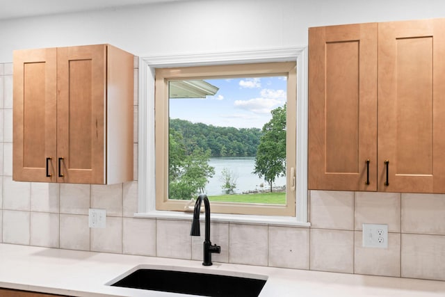 26237 Twin Rivers Dr, Shell Knob, MO 65747 - kitchen with a sink, decorative backsplash, brown cabinets, light stone counters, and a water view