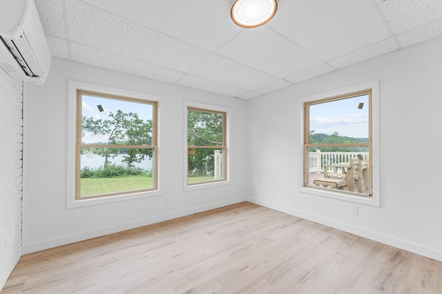 26237 Twin Rivers Dr, Shell Knob, MO 65747 - spare room featuring a paneled ceiling, a wall mounted air conditioner, light wood-style flooring, and baseboards