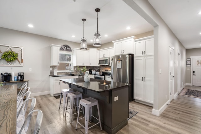 400 Lake Front Dr, Branson, MO 65616 - kitchen featuring appliances with stainless steel finishes, dark countertops, a sink, light wood-style floors, and backsplash