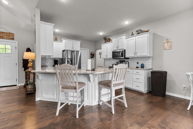 419 Wyldewood Dr, Fordland, MO 65652 - kitchen featuring appliances with stainless steel finishes, a peninsula, tasteful backsplash, white cabinets, and light stone counters