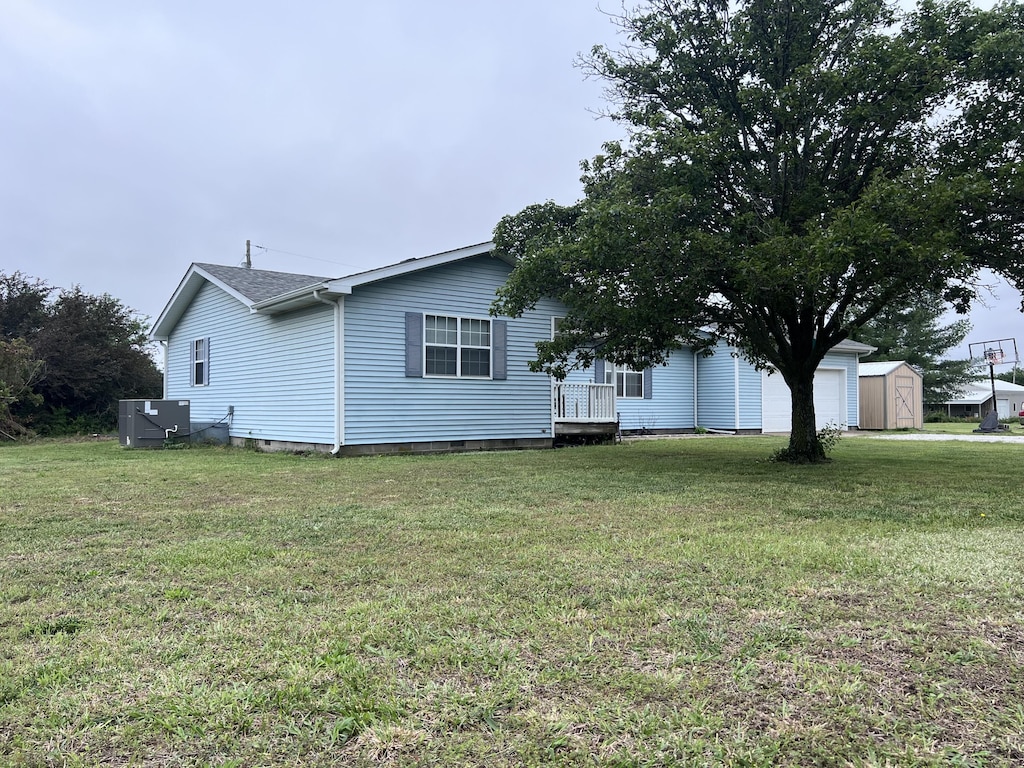 2038 W Trolley Car Ln, Carthage, MO 64836 - view of side of home with a lawn, central AC, an attached garage, a shed, and crawl space