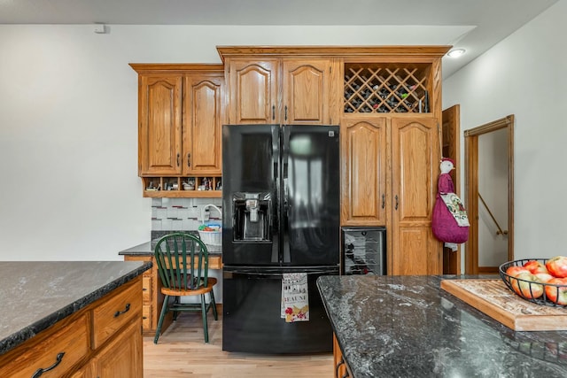 1915 S Farm Rd Unit 219, Springfield, MO 65809 - kitchen featuring black fridge with ice dispenser, dark stone counters, light wood-style floors, brown cabinetry, and tasteful backsplash