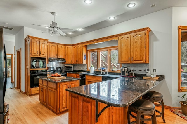 1915 S Farm Rd Unit 219, Springfield, MO 65809 - kitchen with black appliances, under cabinet range hood, brown cabinetry, a peninsula, and recessed lighting