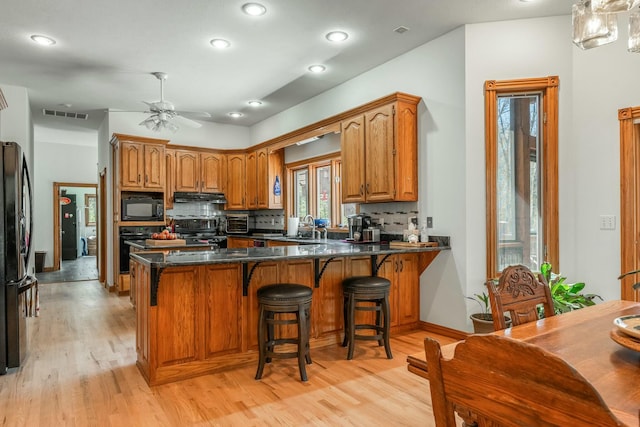 1915 S Farm Rd Unit 219, Springfield, MO 65809 - kitchen with black appliances, brown cabinets, light wood-style flooring, a peninsula, and recessed lighting