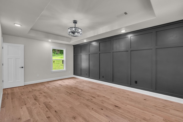 3002 Ginger Dr, West Plains, MO 65775 - unfurnished room with a raised ceiling, a decorative wall, a chandelier, light wood-type flooring, and baseboards