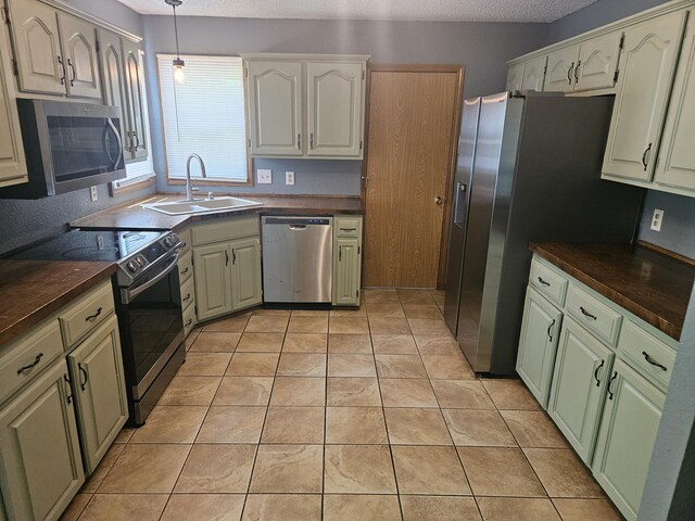 108 Prince St, Buffalo, MO 65622 - kitchen with appliances with stainless steel finishes, a sink, dark countertops, a textured ceiling, and hanging light fixtures