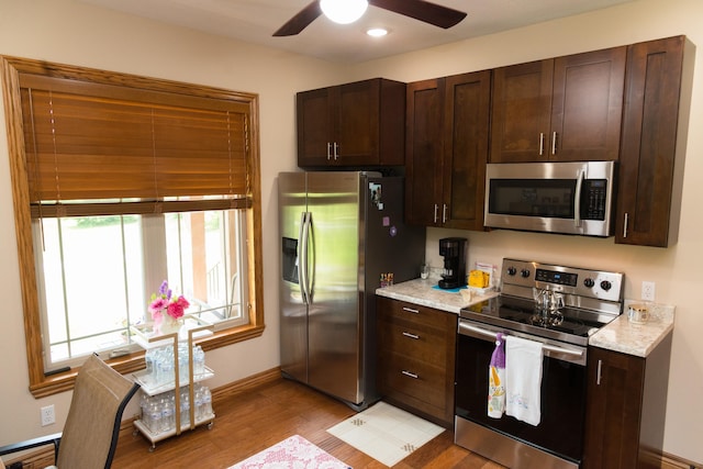 1762 Hickory Ridge Cir, Nixa, MO 65714 - kitchen with appliances with stainless steel finishes, light wood-type flooring, dark brown cabinetry, a ceiling fan, and baseboards