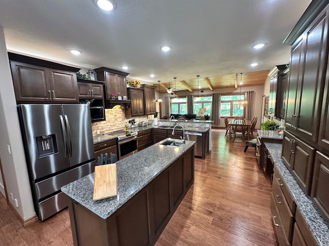 1762 Hickory Ridge Cir, Nixa, MO 65714 - kitchen with appliances with stainless steel finishes, a peninsula, wood finished floors, tasteful backsplash, and recessed lighting