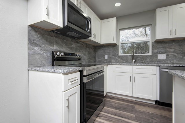 304 Rice St, Nixa, MO 65714 - kitchen with appliances with stainless steel finishes, a sink, dark wood-style floors, white cabinetry, and tasteful backsplash