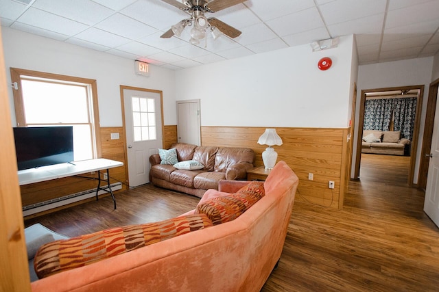 19429 E State Highway 14, Ava, MO 65608 - living room featuring a paneled ceiling, wood finished floors, wainscoting, a ceiling fan, and a baseboard heating unit