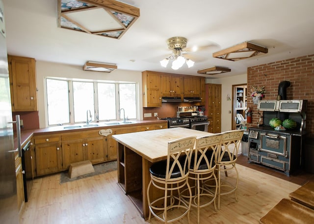 19429 E State Highway 14, Ava, MO 65608 - kitchen with a wood stove, butcher block countertops, a sink, stainless steel stove, and light wood-type flooring