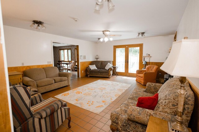 19429 E State Highway 14, Ava, MO 65608 - living room with wainscoting, french doors, wood walls, a ceiling fan, and tile patterned flooring