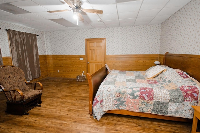 19429 E State Highway 14, Ava, MO 65608 - bedroom with wood finished floors, a wainscoted wall, a paneled ceiling, wallpapered walls, and ceiling fan