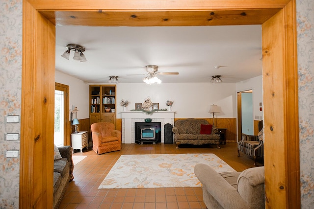 19429 E State Highway 14, Ava, MO 65608 - living area with a glass covered fireplace, a wainscoted wall, a ceiling fan, and tile patterned flooring