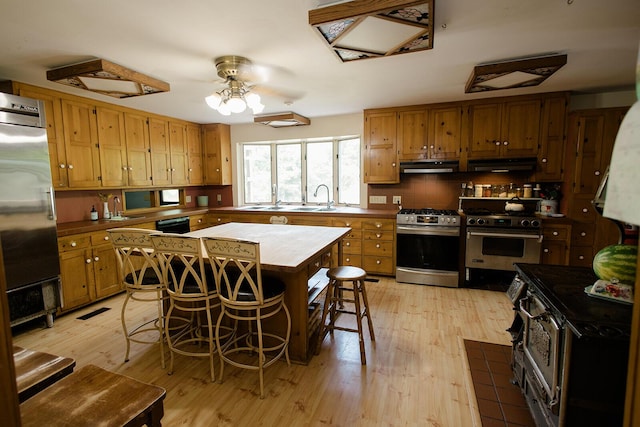 19429 E State Highway 14, Ava, MO 65608 - kitchen with premium appliances, under cabinet range hood, light wood-type flooring, and brown cabinets
