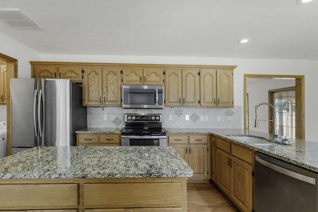 1605 S Meadowview Ave, Springfield, MO 65804 - kitchen featuring appliances with stainless steel finishes, a sink, light wood-style flooring, tasteful backsplash, and light stone counters