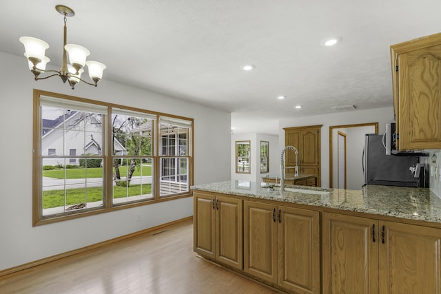 1605 S Meadowview Ave, Springfield, MO 65804 - kitchen featuring a sink, a peninsula, light wood-style floors, a chandelier, and light stone countertops