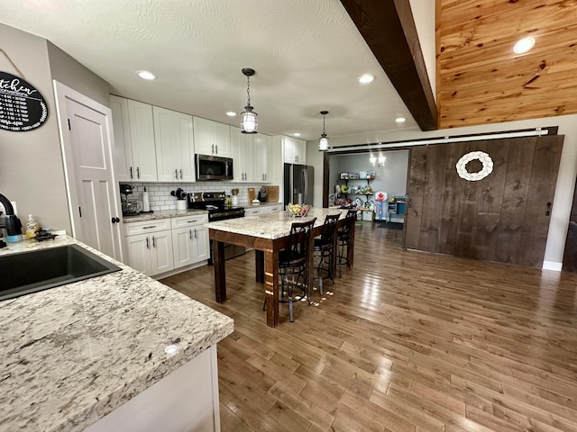 923 Riverview Rd, Marshfield, MO 65706 - kitchen with appliances with stainless steel finishes, a sink, white cabinetry, a breakfast bar, and dark wood finished floors