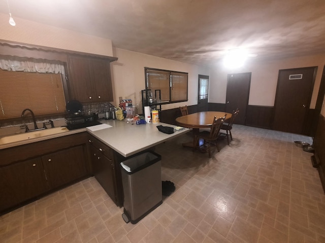 2504 N Clayton Ave, Springfield, MO 65803 - kitchen featuring a sink, dark brown cabinetry, a peninsula, light countertops, and wainscoting