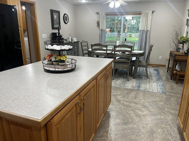 4120 S 119th Rd, Bolivar, MO 65613 - kitchen featuring brown cabinetry, a ceiling fan, freestanding refrigerator, light countertops, and a center island