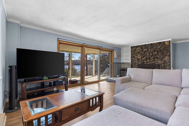 25451 County Road 327, Urbana, MO 65767 - living area featuring wood finished floors, a textured ceiling, ornamental molding, an AC wall unit, and a stone fireplace