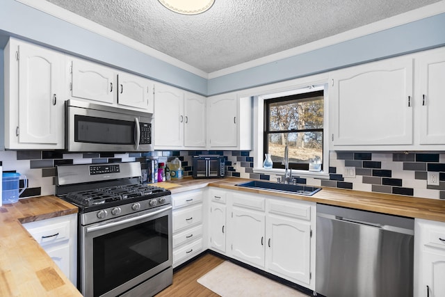 25451 County Road 327, Urbana, MO 65767 - kitchen with butcher block countertops, stainless steel appliances, a textured ceiling, a sink, and white cabinetry